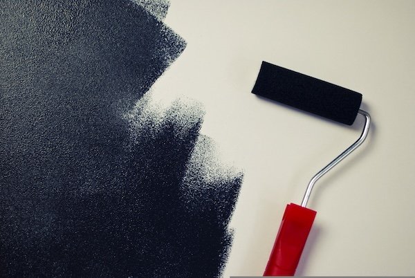 Paint roller applying fresh paint to a wall